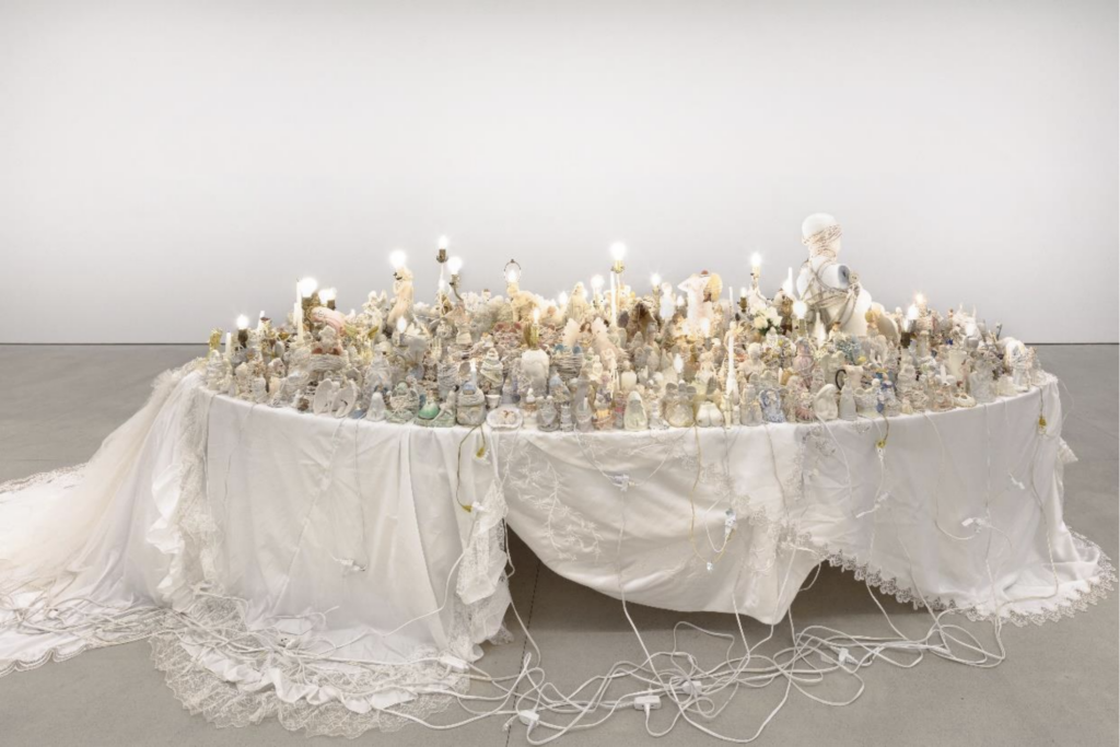 PORTIA MUNSON, Bound Angel, 2021. Found figurines, lamps, candles, string & rope, wedding gowns as tablecloth, extension cords, oval table. 4.88 x 1.73 x 1.68 m. Courtesy of the artist and P-P-O-W, New York. Photo: Lance Brewe